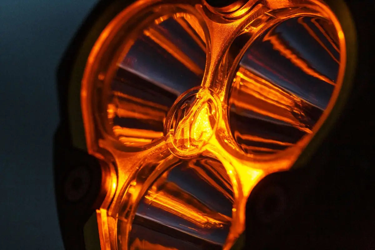 Close-up of FLEX ERA® 3 LED light pod emitting amber light, highlighting its high-performance lens and rugged design.
