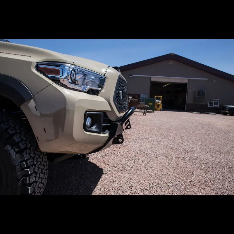 Angled view of a Toyota Tacoma with a Lo-Pro winch bumper, emphasizing its rugged construction and compatibility with 2016+ models.