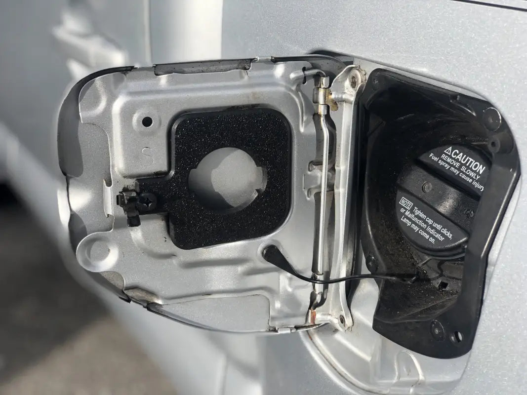 Carbon fiber-style gas cap holder insert for Toyota Tacoma 2005-2023, securely mounted in the fuel door.