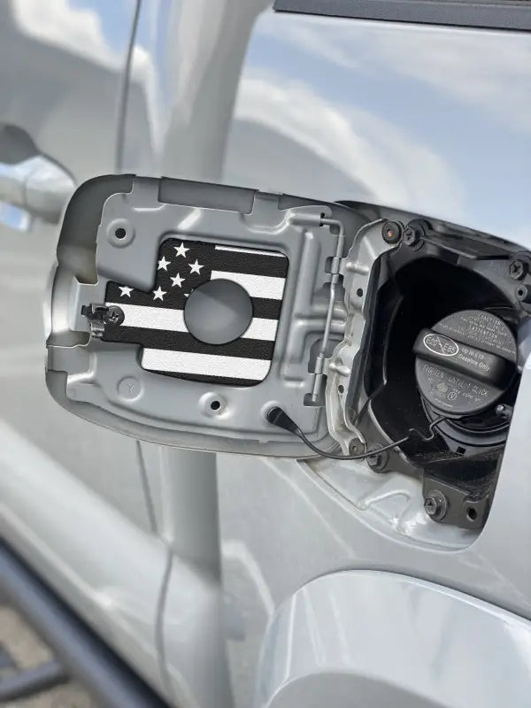 Gas cap holder insert with full-color American flag design for Toyota Tacoma 2005-2023, mounted inside the fuel door.