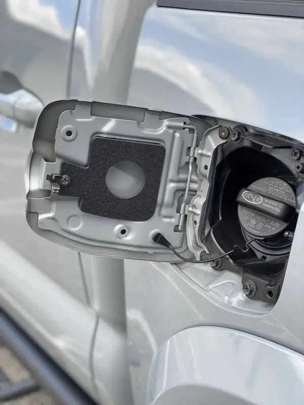 Gas cap holder insert for Toyota Tacoma 2005-2023, black textured finish, installed in the fuel door compartment.