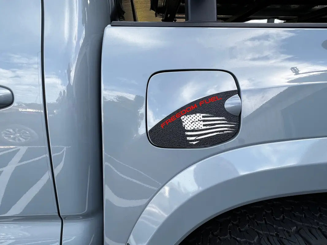 Gas lid protection overlay with black texture and 'Freedom Fuel' text in red alongside an American flag design, fits 2016-2023 Toyota Tacoma.