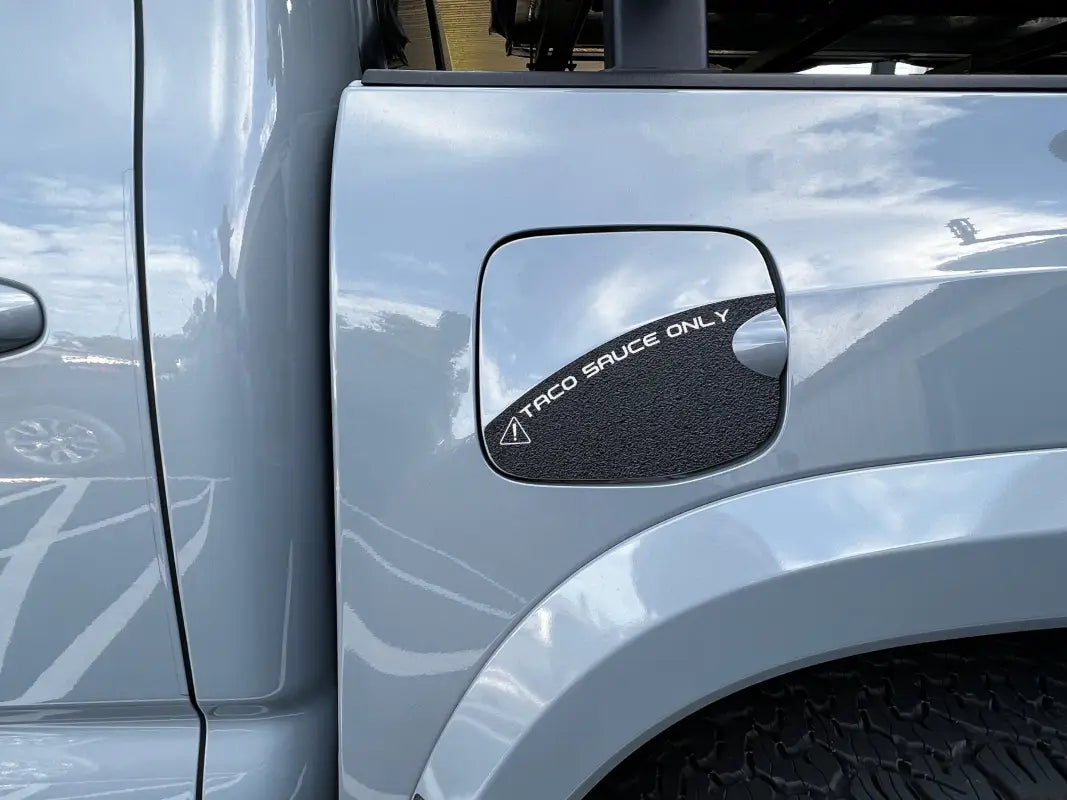 Gas lid protection overlay with black texture and 'Taco Sauce Only' text in white, fits 2016-2023 Toyota Tacoma.