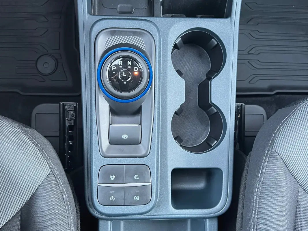 Gear selector accent overlay on car’s center console with gear shift and cupholders in Ford Maverick
