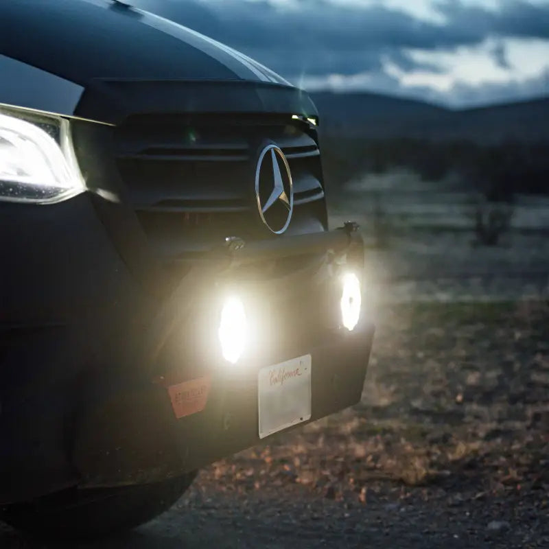 Close-up of Gravity Titan 6-inch LED lights in amber mode mounted on a Mercedes Sprinter van for off-road use.