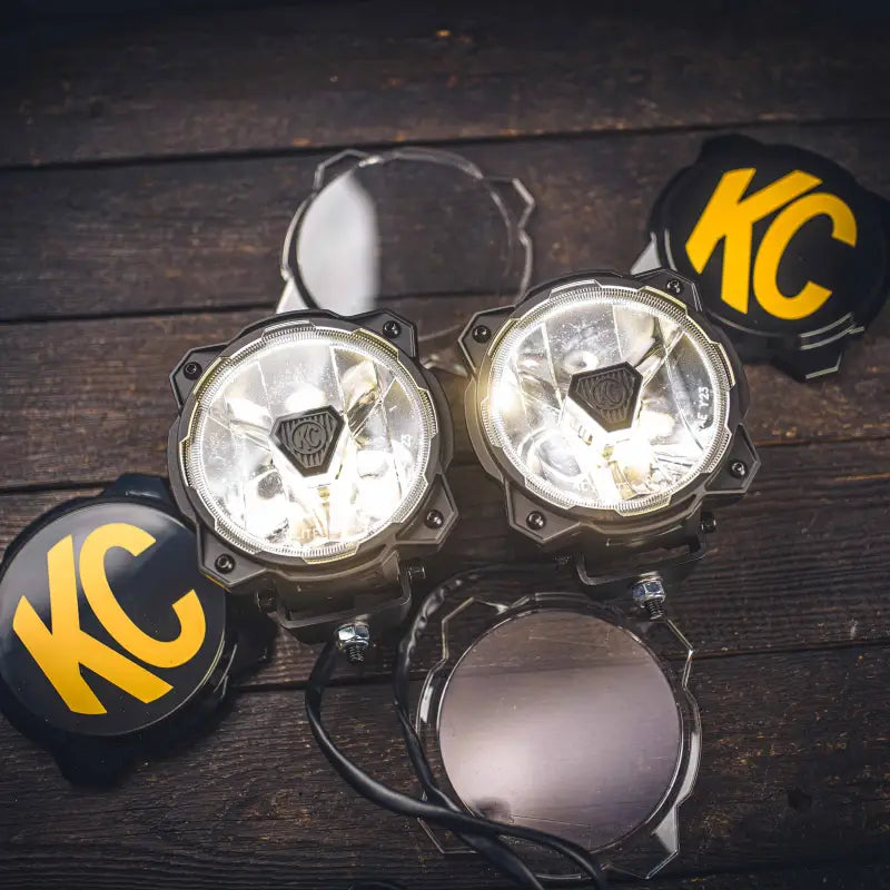 Close-up of Gravity Titan 6-inch LED lights with clear lenses, KC logo covers, and durable construction for off-road use.