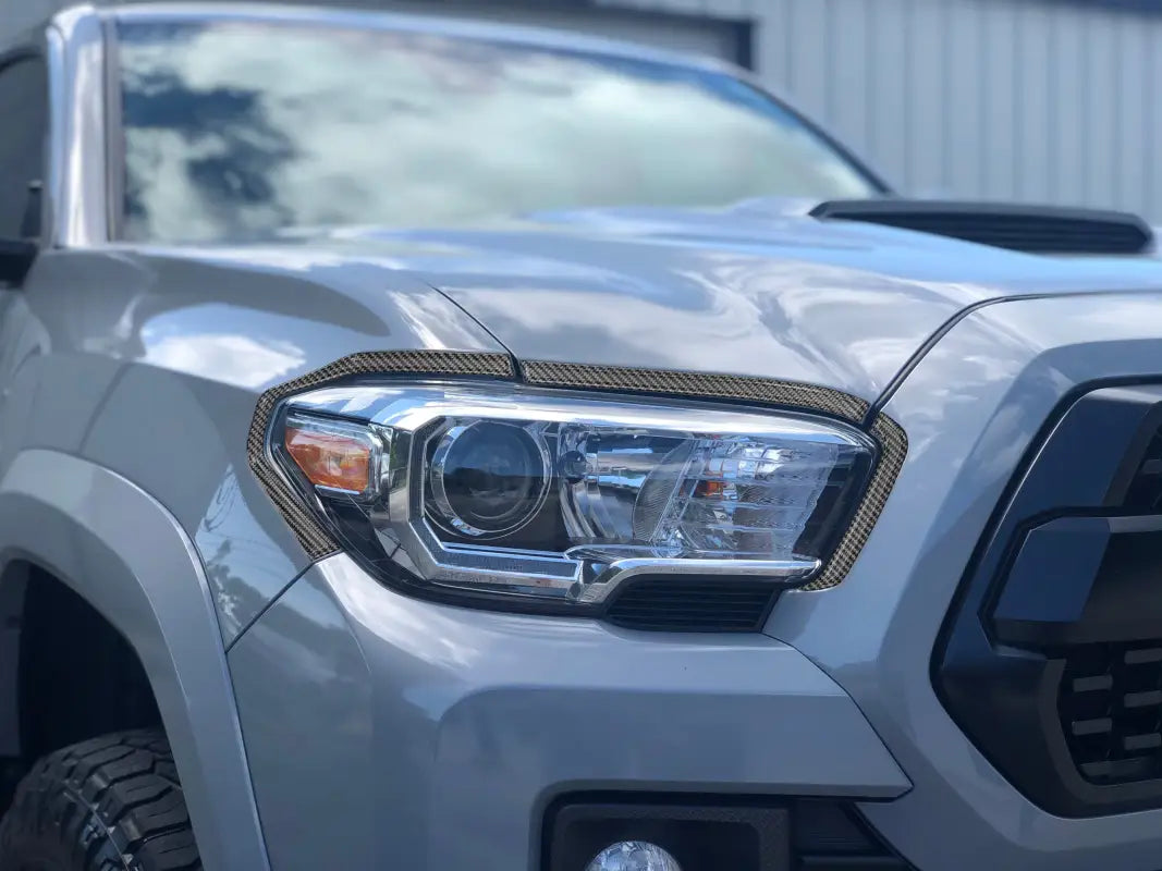 Close-up of headlight accent overlays on a 2016-2023 Toyota Tacoma, showcasing a sleek carbon fiber design.