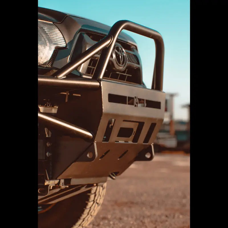 Close-up of hybrid front bumper on Toyota Tacoma, showing durable steel construction and bolt-on design for 2012-2015 models.
