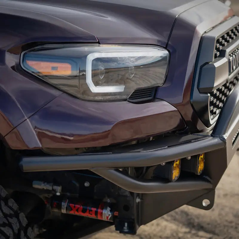 Side angle of a 3rd Gen Tacoma hybrid front bumper, showcasing steel build, yellow fog lights, and winch mount compatibility.
