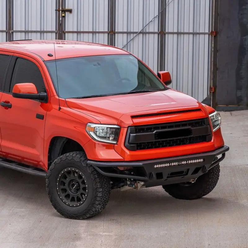 Orange Toyota Tundra with hybrid front bumper, LED bar, and fog lights, designed for 2014-2021 models, parked on concrete.