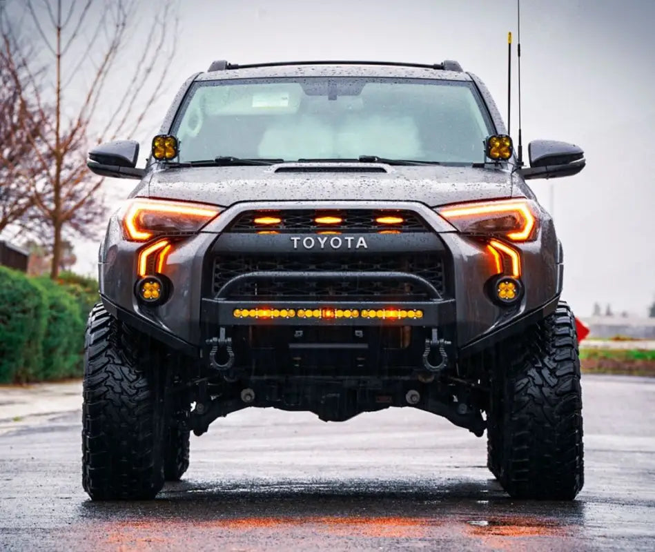 Toyota 4Runner with LED DRL Fang Light Bezel Kit in amber, illuminated in rainy conditions, emphasizing durability and improved visibility.