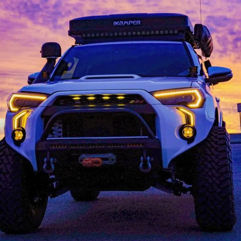 Toyota 4Runner with LED DRL Fang Light Bezel Kit in amber, illuminated at sunset, emphasizing enhanced style and safety for off-road adventures.
