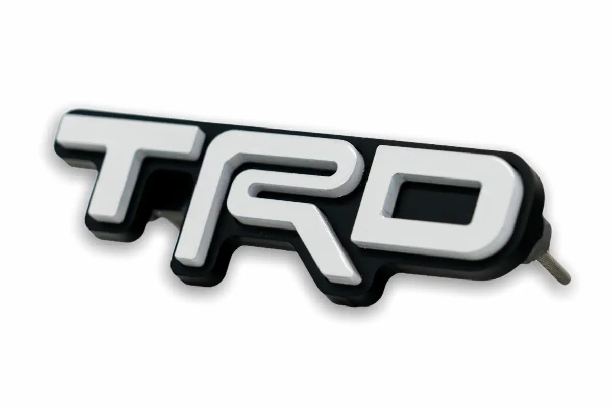 White and black TRD emblem logo grille badge for route protection enhancement