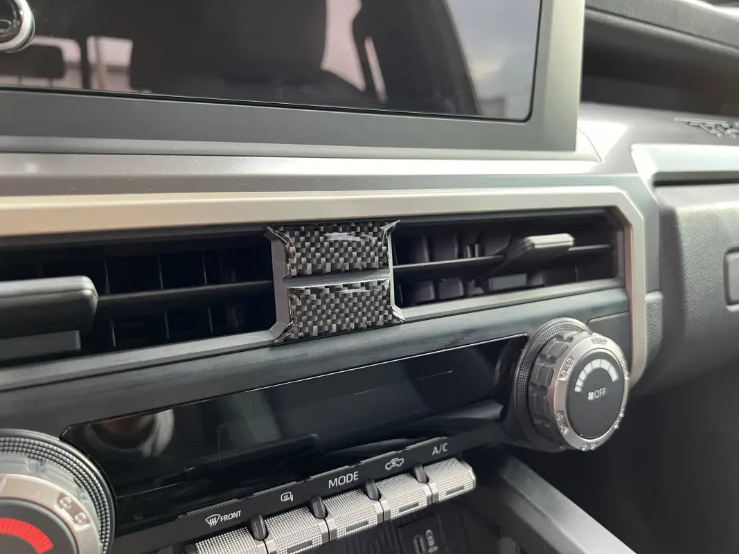 Close-up of carbon fiber middle A/C vent accent trim fitted on a 2024 Toyota Tacoma, showcasing a sleek and modern look.