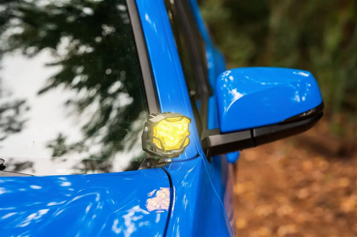 Morimoto HXB 4Banger Ditch Light mounted on a blue Tacoma 2016-2023, showcasing its compact design and yellow illumination.