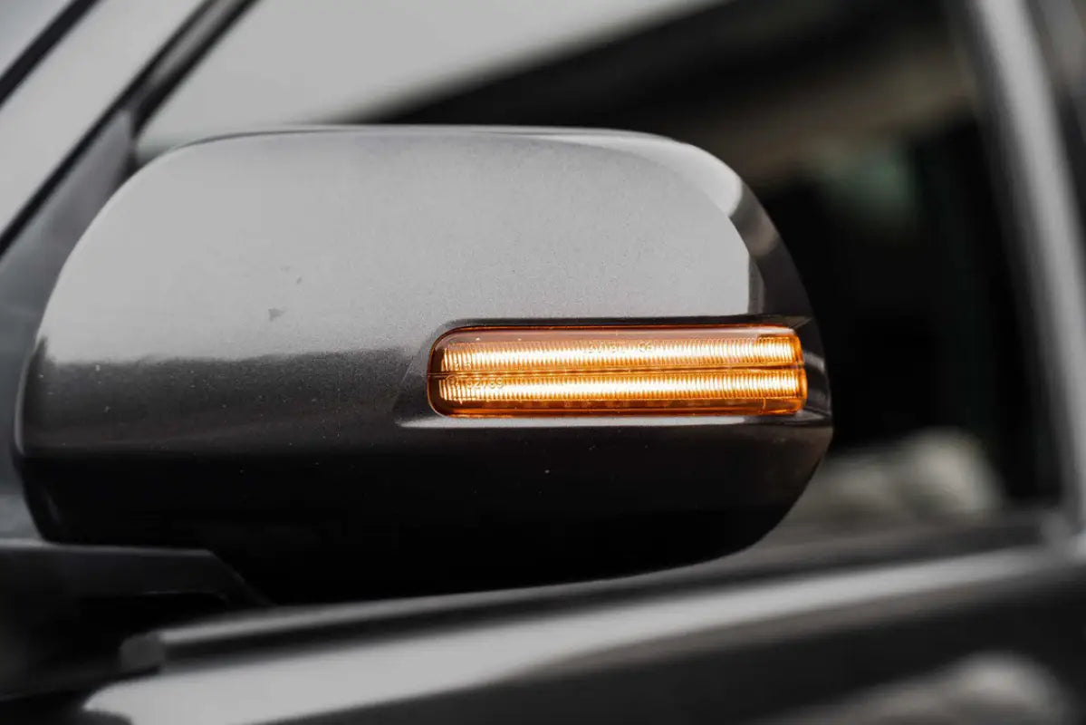 Morimoto XB turn signal illuminated in amber on a side mirror of a Tacoma or 4Runner, highlighting its bright output.