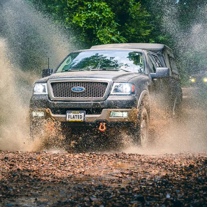Truck with MR Full-Size 5.5' Bed air-topper shell driving through muddy terrain, highlighting its durability and off-road compatibility.