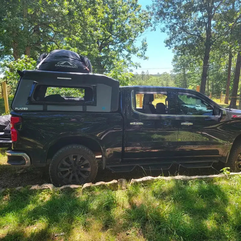 Black truck parked outdoors with MR Full-Size 5.5' Bed air-topper shell installed, carrying additional cargo on top.