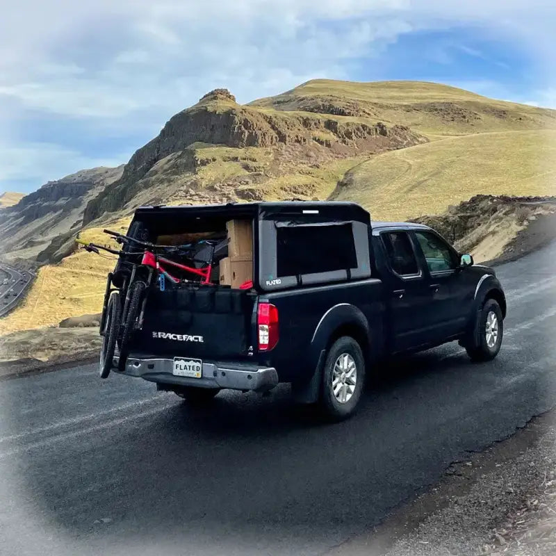 MR - Mid-Size 6'-Long Bed inflatable truck shell on a black Frontier truck carrying bikes, highlighting its utility for outdoor adventures.