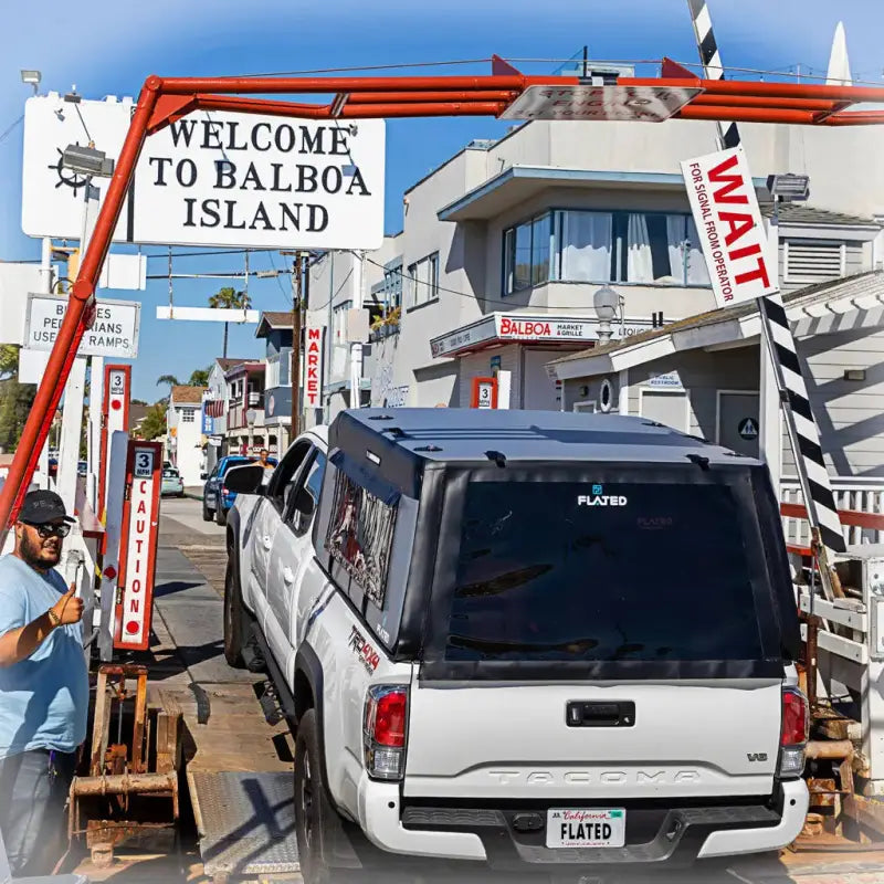MR - Mid-Size 6'-Long Bed inflatable truck shell on a white Tacoma truck entering Balboa Island, illustrating its travel-friendly design.