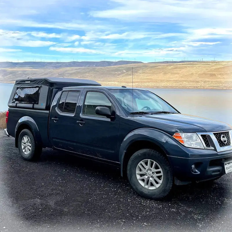 MR - Mid-Size 6'-Long Bed inflatable truck shell installed on a black Frontier truck near a lake, showcasing its adaptability to different vehicles.