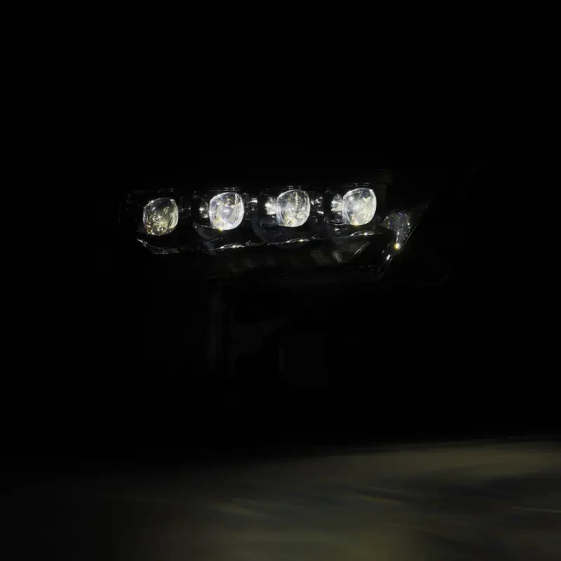 Close-up of AlphaRex NOVA-Series LED projector headlight with bright white beam, designed for 22-24 Toyota Tundra and Sequoia.