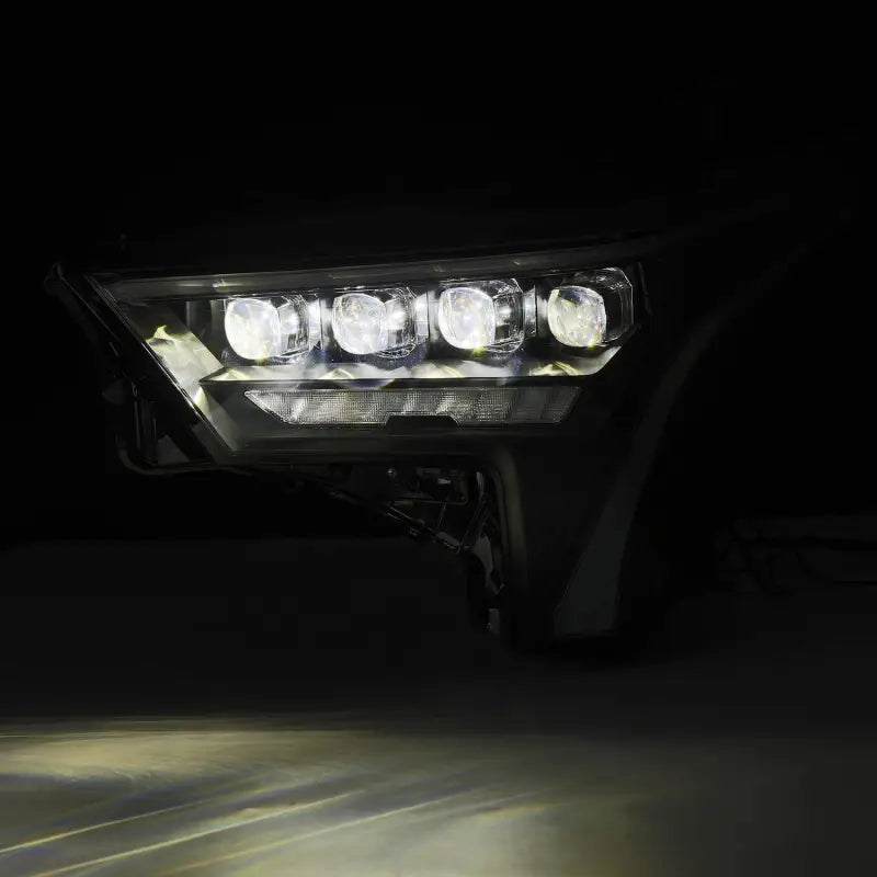 AlphaRex NOVA-Series LED projector headlight illuminated in a dark setting, demonstrating its powerful and clear light output.