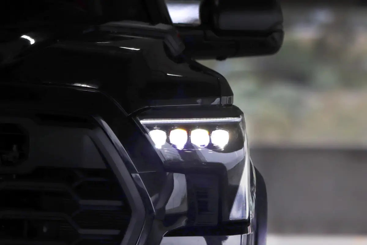 AlphaRex NOVA-Series LED projector headlights illuminated on a Toyota Tundra in a low-light setting, demonstrating powerful lighting performance.