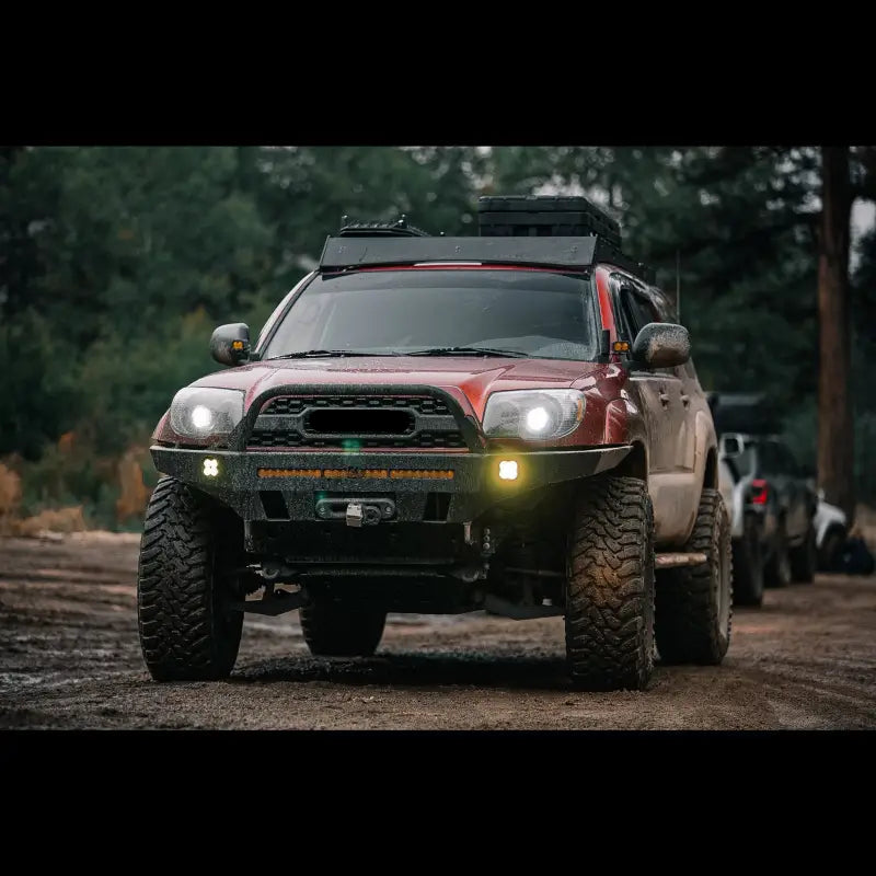 Front view of 4Runner with Overland Series Front Bumper on a muddy trail, featuring LED lights and robust construction.