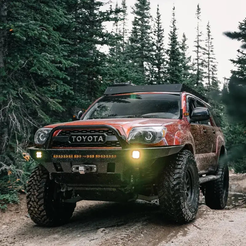 2003-2009 4Runner with Overland Series Front Bumper on a rugged forest trail, showcasing off-road durability and LED lighting.