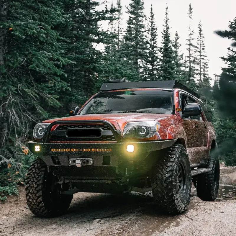 2003-2009 4Runner with Overland Series Front Bumper on a rugged forest trail, showcasing off-road durability and LED lighting.