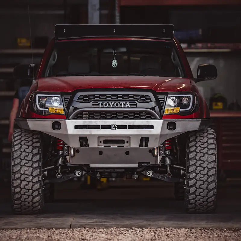 Close-up of a red Toyota Tacoma fitted with Tacoma Overland Series front bumper, emphasizing its durable frame supports and sleek finish.
