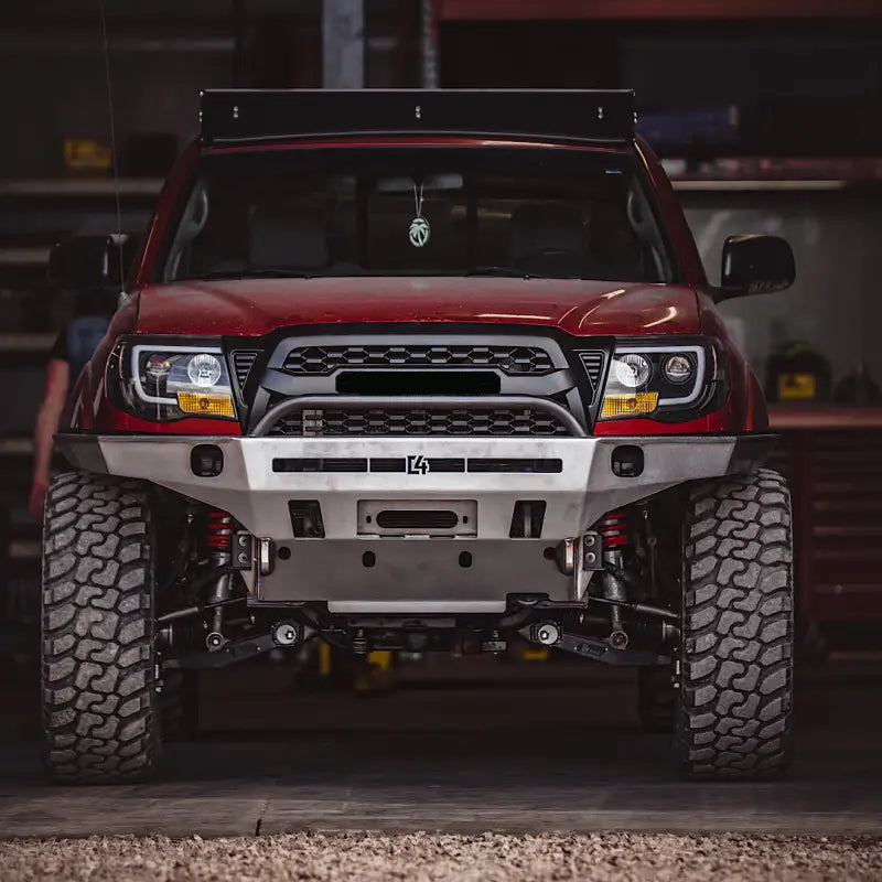 Close-up of a red Toyota Tacoma fitted with Tacoma Overland Series front bumper, emphasizing its durable frame supports and sleek finish.