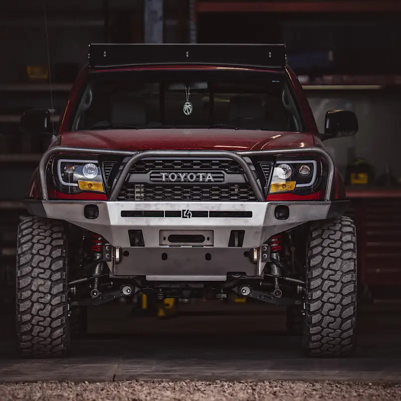 Garage view of a red Toyota Tacoma featuring the Tacoma Overland Series front bumper, designed for 2005-2015 models with improved clearance.