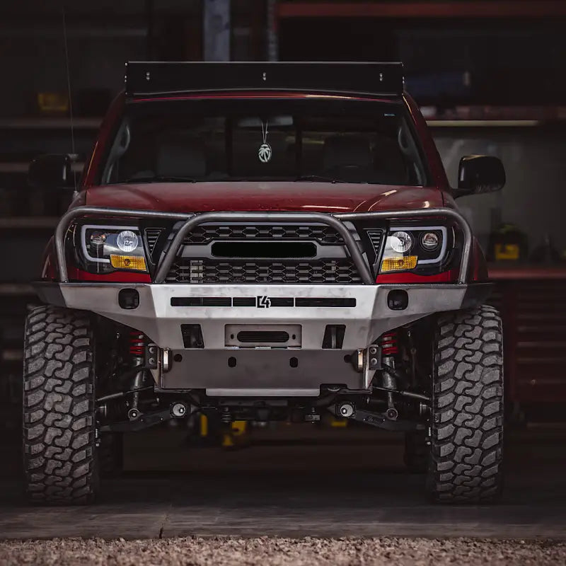Garage view of a red Toyota Tacoma featuring the Tacoma Overland Series front bumper, designed for 2005-2015 models with improved clearance.