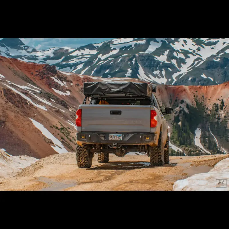 2014-2021 Tundra with Overland Rear Bumper, steel build, OE hitch fit, and light cutouts, parked on a mountain trail.