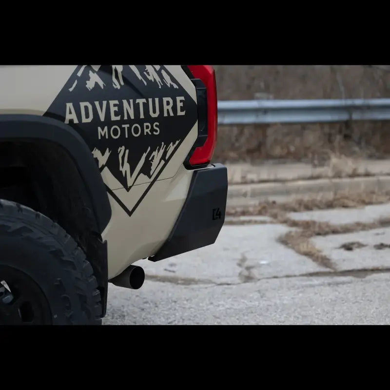 Close-up of black steel Tundra Overland Rear Bumper for 2022+ models, installed on beige truck with Adventure Motors branding.