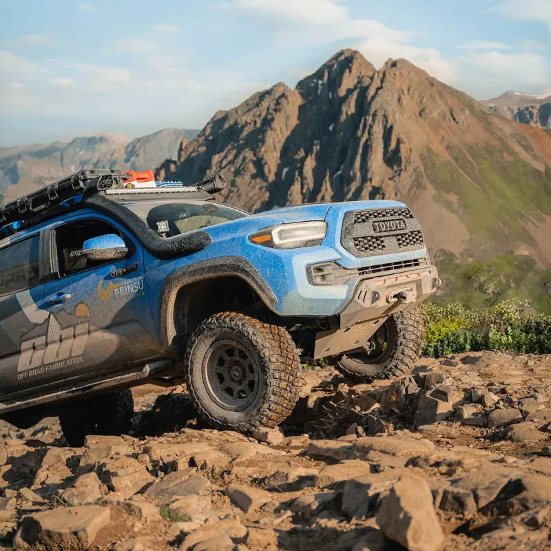 Toyota Tacoma with Prinsu Cab Rack navigating rocky terrain, emphasizing durability and off-road capability.
