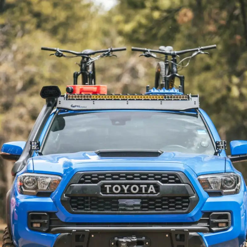 Front view of Toyota Tacoma with Prinsu Cab Rack carrying bikes and accessories, showcasing modular design and desert air intake fitment.