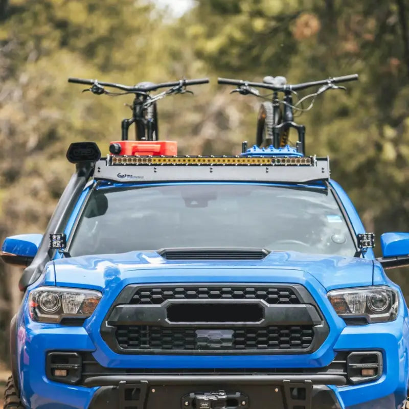 Front view of Toyota Tacoma with Prinsu Cab Rack carrying bikes and accessories, showcasing modular design and desert air intake fitment.