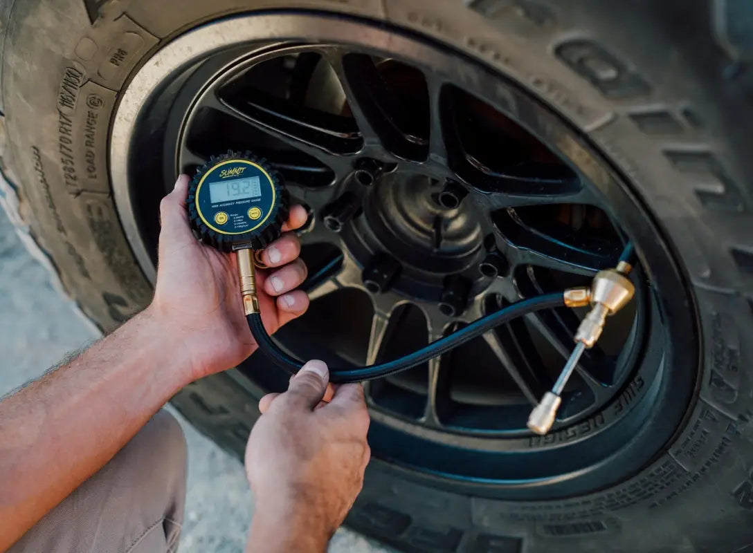 Quick Air Down Tool in use, connected to a vehicle tire for precise air pressure measurement and adjustment during off-road activities.