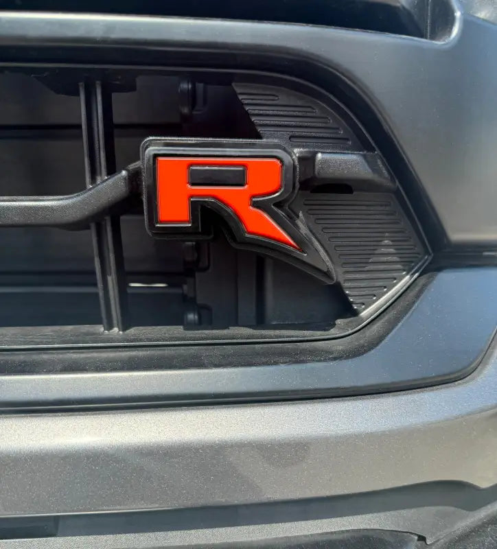 Red and black R emblem insert on Ford F-150 grill for custom styling