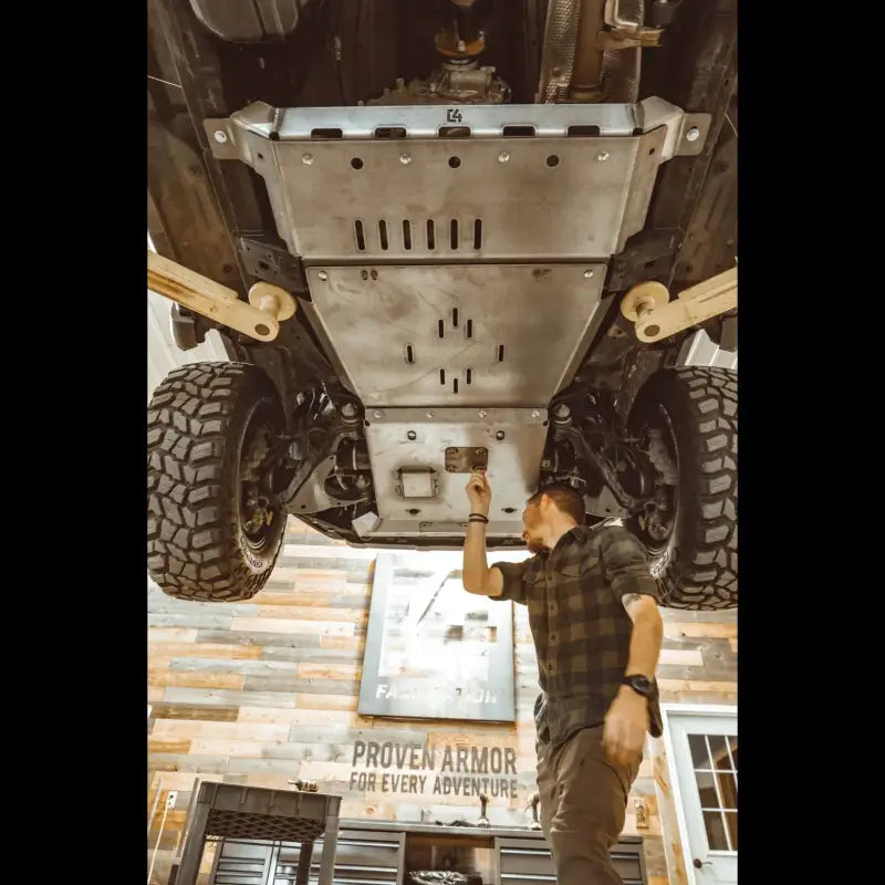 Mechanic inspecting installed 4Runner rear skid plates for 5th Gen 2010+, designed for strength and off-road protection.
