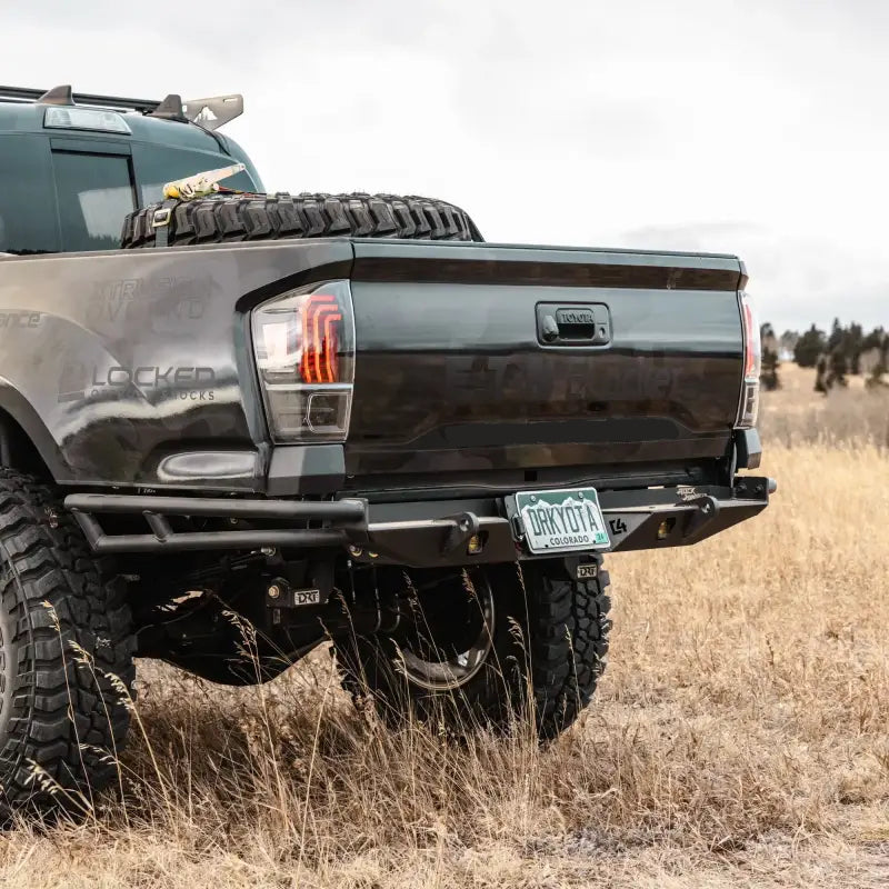 Tacoma Rock Runner rear bumper installed on a black 3rd Gen Tacoma, showcasing high-clearance modular design in an outdoor setting.