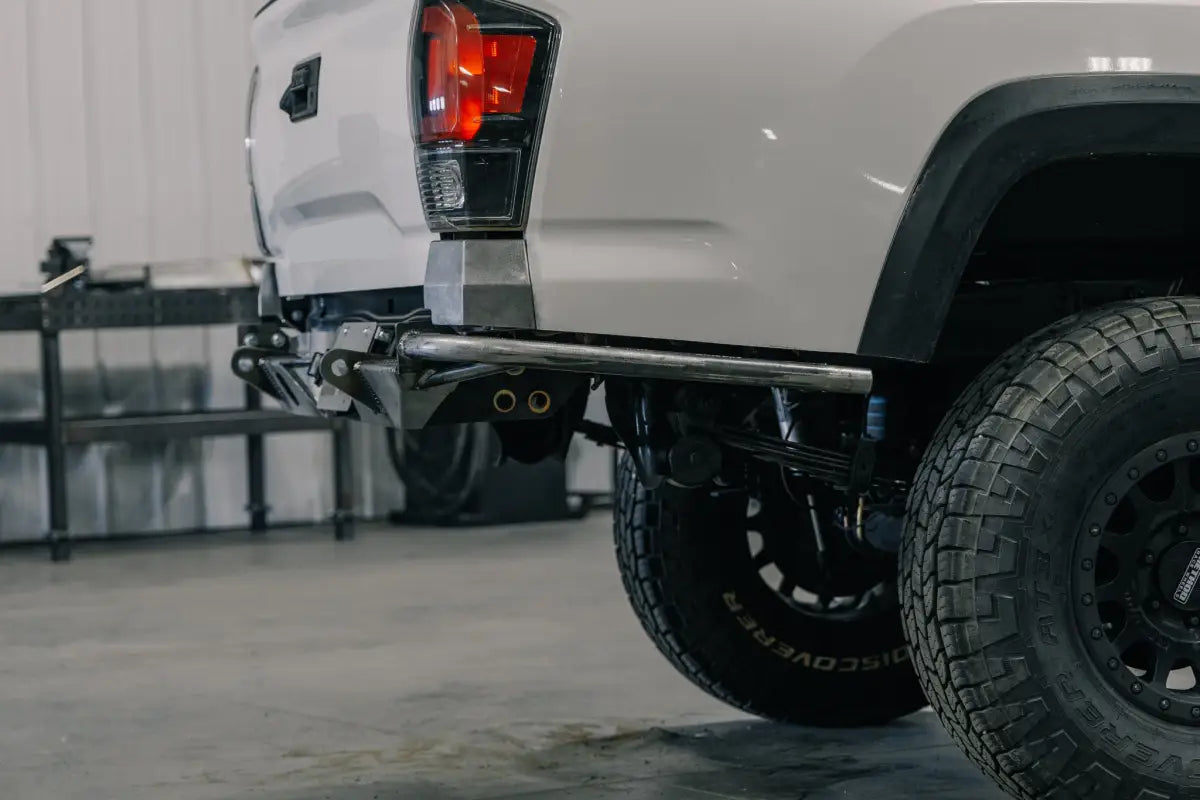 Slanted single tube Tacoma Rock Runner rear bumper installed on a white 3rd Gen Tacoma, highlighting minimalist high-clearance design.