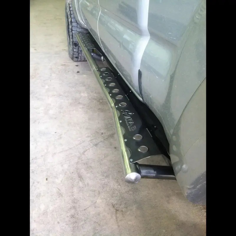 Close-up of Tacoma rock sliders for 2005-2015 models on a light green truck, highlighting the durable steel tubing and bolt-on design.