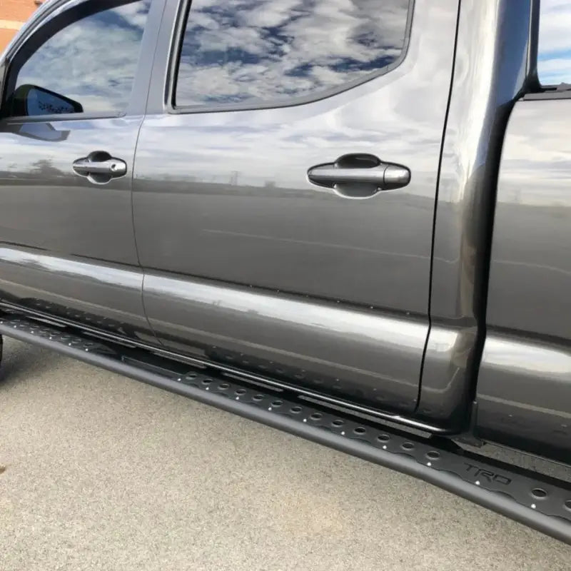 Tacoma rock sliders for 2005-2015 models installed on a gray truck, featuring a bolt-on design with durable DOM tubing.