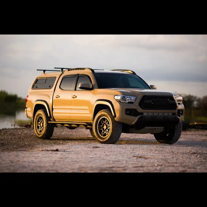 2016+ Toyota Tacoma with bolt-on rock sliders parked outdoors. Features rugged sliders ideal for off-road use and hi-lift jacks.