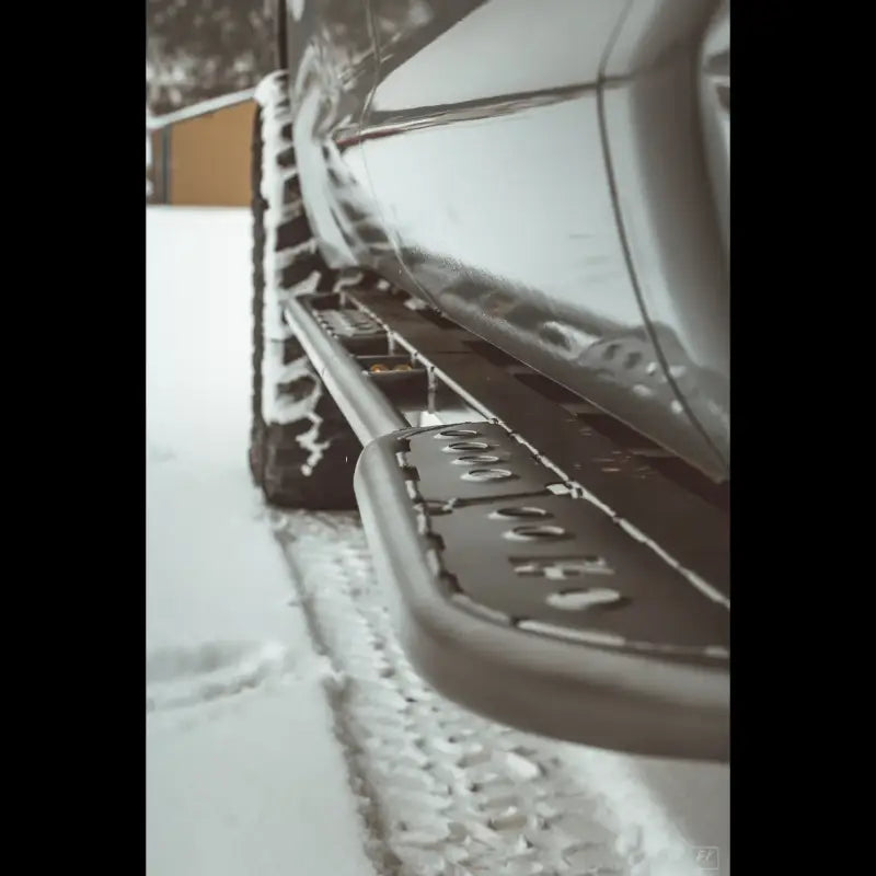 Close-up of Tundra 2nd Gen rock sliders in snow, highlighting durable construction and bolt-on installation.