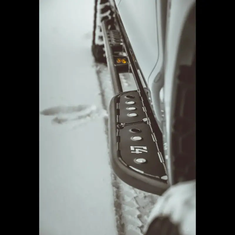 Side view of Tundra 2nd Gen rock sliders in snow, featuring step plate design and rugged durability.
